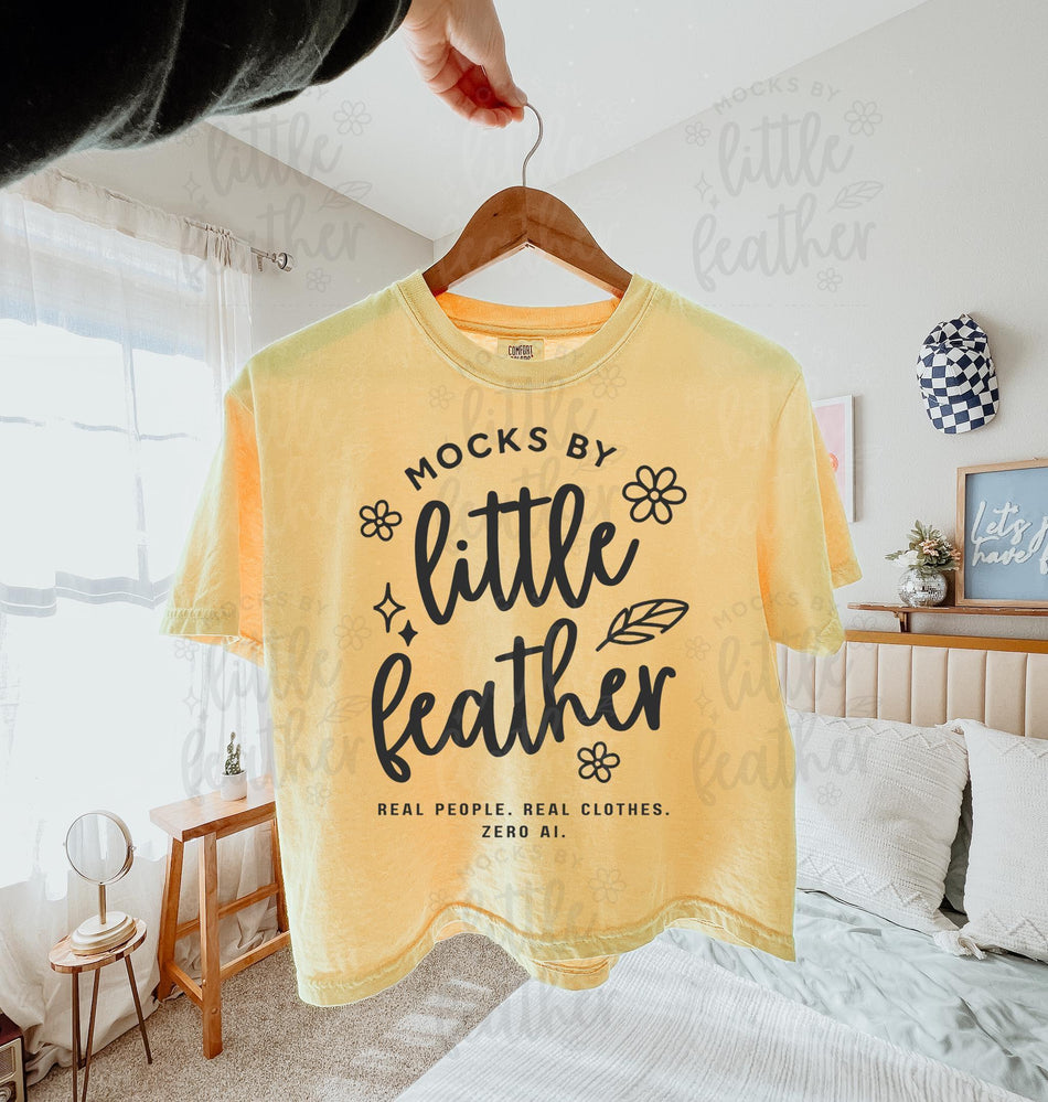 a butter comfort colors 3023cl t-shirt with bold white text that says 'Mocks by Little Feather – Real People. Real Clothes. Zero AI.' surrounded by doodle-style flowers and feathers. Trendy Etsy-style mockup featuring real product photography for print-on-demand sellers.